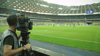 Cameraman with a camera in the stadium during a football match. TV